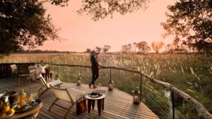 Botswana-Sandibe-Guest-Area-deck-guest-viewing-the-sunset-Website-1920x1080-fill-gravityauto - Go Do Africa